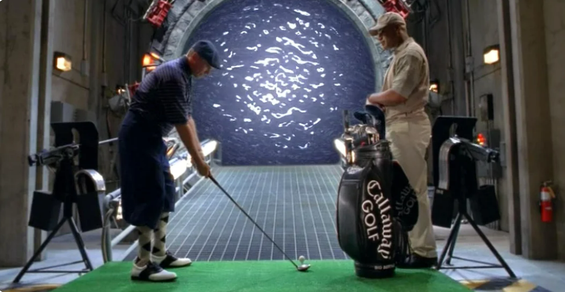 Richard Dean Anderson as Jack O&rsquo;Neill in the Stargate SG1 show, in a golf suit, trying to do
a backswing through the opened Stargate